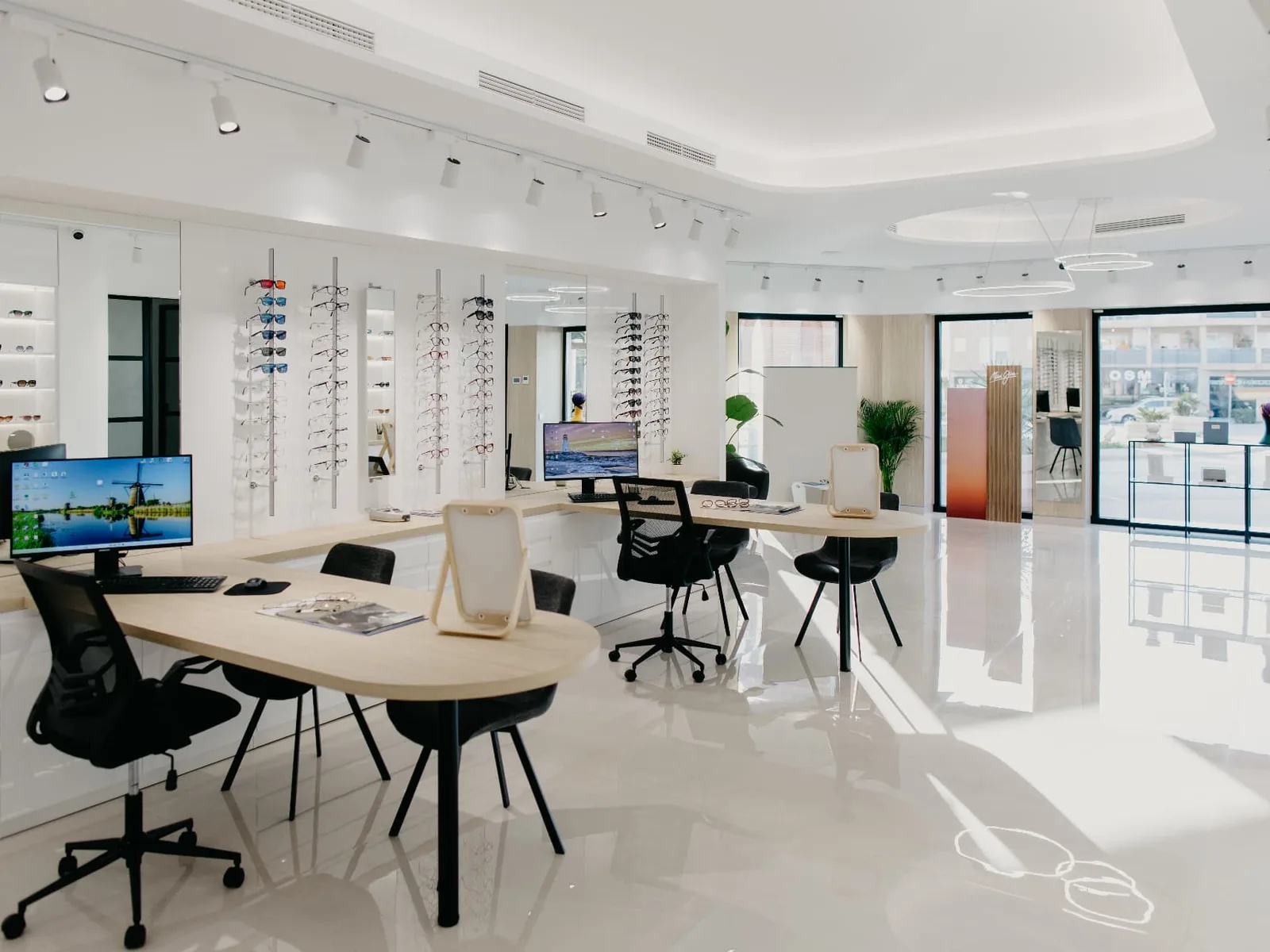 Interior luminoso del Centro Óptico Sabio en Vícar con expositores de gafas y mesas de atención